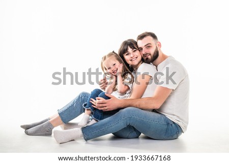 Young family with daughter have fun together sitting on the floor with hearth sign isolated on white background