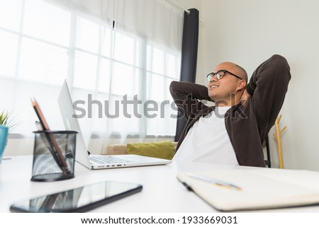 Young asian businessman finish the job turn off laptop and take a rest. Indian freelancer finished his work and take a break. He work at home. Royalty-Free Stock Photo #1933669031