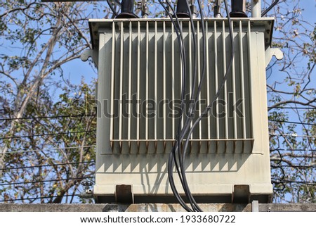 Large high voltage transformers mounted on concrete beams and power poles.