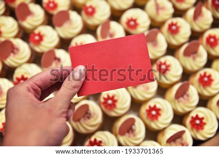 Cupcakes in the box and hand with blank card. Confectionery company. Empty business card.