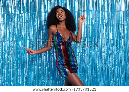 Portrait of attractive cheerful carefree girl having fun dancing festal event isolated over blue tinsel curtain background Royalty-Free Stock Photo #1933701521