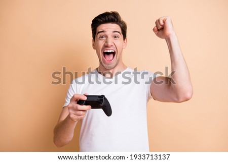 Portrait of addicted handsome guy fist up open mouth celebrate result isolated on beige color background