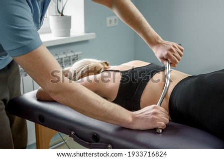 IASTM treatment, girl receiving soft tissue treatment on her neck with stainless steel tool Royalty-Free Stock Photo #1933716824