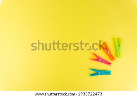 Plastic clothespins for hanging clothes of different colors on a yellow background