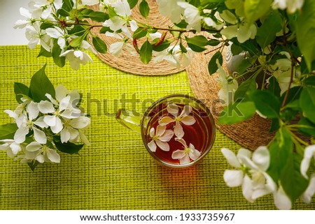 Flatlay. Yellow-green wicker background, a lot of apple blossoms and a mug of tea with flowers. Inspirational spring - a time of dreams and hopes