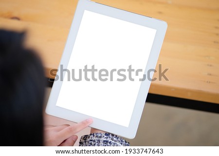 Woman shopping on-line by using iPad at home.Top view mockup image of a woman sitting and holding black tablet pc with blank white desktop screen