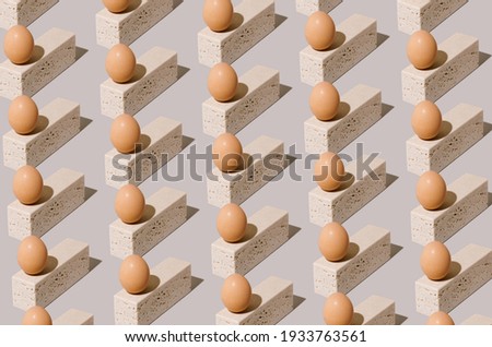 Easter egg pattern made of natural eggs on top of travertine marble blocks on a gray background. 2021 unique still life concept. Surreal vintage food composition.