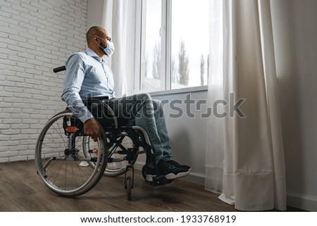Disabled man sitting in a wheelchair and wearing face mask