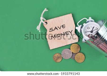 Clock, coins and wooden tag written with SAVE MONEY.