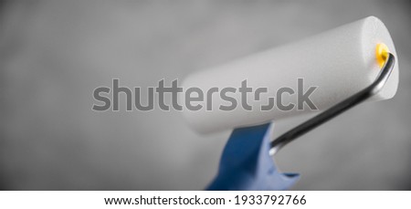 Clean fresh new paint roller for painting on gray blurred concrete background. Close up with copy empty space for text. Banner for advertising