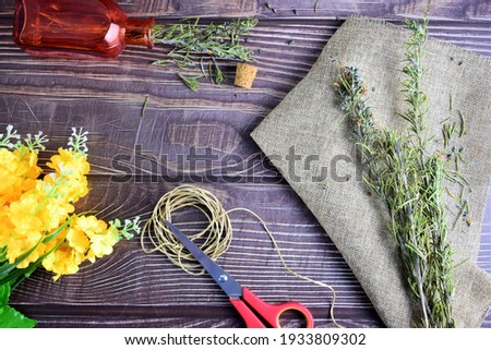 On rustic table, rosemary branches, flowers, to manipulate.