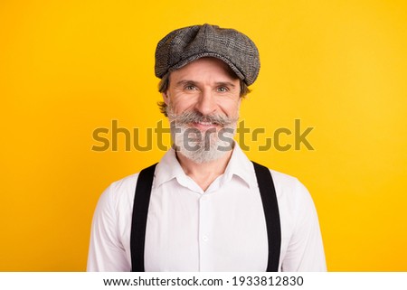 Photo portrait of bearded man wearing grey cap shirt suspenders smiling happy isolated on vivid yellow color background
