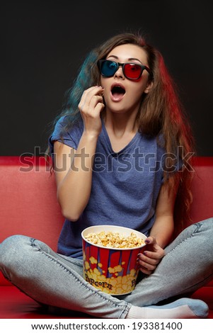 Beautiful girl watching movie with glasses and eating.