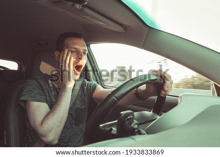 Drunk driver yawning and falling asleep rushes at high speed along road, breaking the rules and speeding violation. Drug intoxication while driving in motion. Problems and risk of accident. Royalty-Free Stock Photo #1933833869