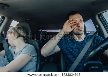 Bored people drive a car together, yawning and struggling to sleep while holding the wheel. Drowsiness and depression of the driver, the need to rest and stop. Royalty-Free Stock Photo #1933834913