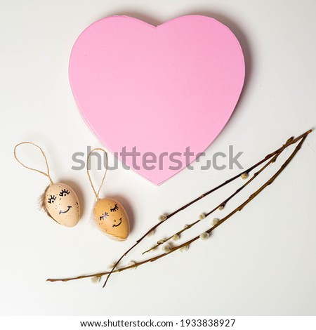 Beautiful composition of a sprig of pussy willow and eggs with a drawn cute face and heart