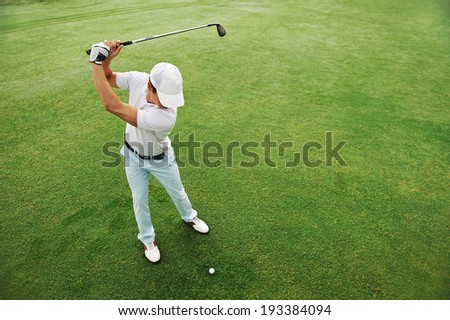 High overhead angle view of golfer hitting golf ball on fairway green grass Royalty-Free Stock Photo #193384094