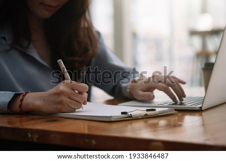 Remote student. Focused young indian lady wearing headphones practice in distant learning of english language write test before pc screen. Hindu woman in earphones listen to webinar online take notes Royalty-Free Stock Photo #1933846487