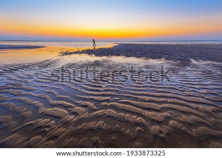 Magical morning seascape with rising Sun, water ripple and sand patterns, shallow, low tide. Exotic beach on Koh Samui island, Thailand.
