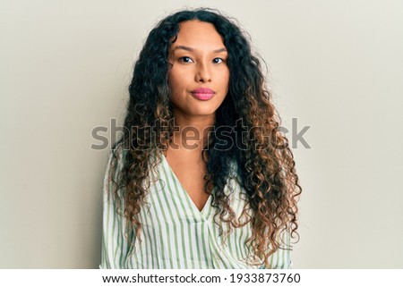 Young latin woman wearing casual clothes relaxed with serious expression on face. simple and natural looking at the camera. 