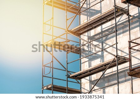 Scaffolding on multi storey building facade during facade renovation. Bright sunny day. Royalty-Free Stock Photo #1933875341