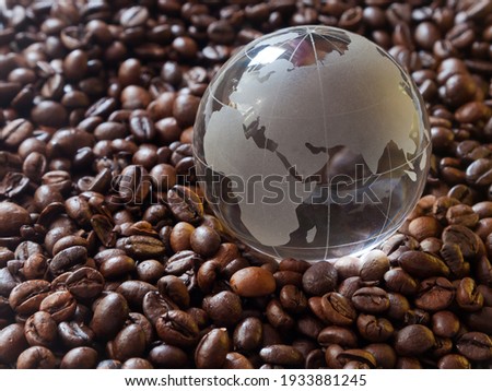 Glass earth globe Africa and Asia in centre closeup among coffee beans background. African countries exporters of cofe beans