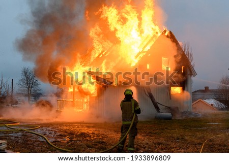 Norwegian firefighter trying to put out flames house on fire Royalty-Free Stock Photo #1933896809