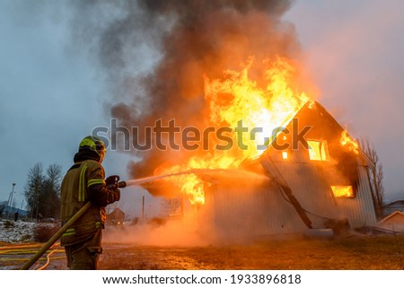 Norwegian firefighter trying to put out flames house on fire Royalty-Free Stock Photo #1933896818