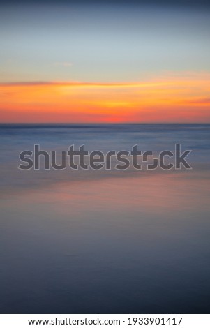 Sunset seascape. Slow shutter speed. Colorful sky. Amazing water reflection. Nature and environment background. Soft focus. Silky water. Copy space. Beach in Bali, Indonesia.