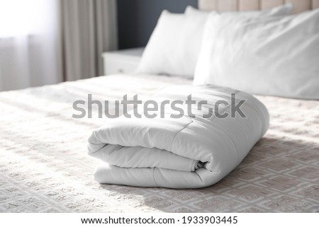 Folded clean blanket on bed in room Royalty-Free Stock Photo #1933903445