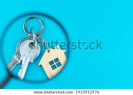 Find a home or a flat concept. Toy model house under magnifying glass. Rent apartments, Real Estate and buying a house idea. Blue background