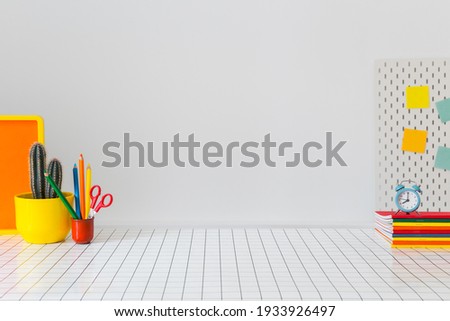 Student creative desk mock up with colorful office supplies, laptop and blue wall. Back to school. Royalty-Free Stock Photo #1933926497