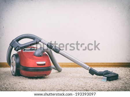 Red vacuum cleaner in empty room. Photo with vignette.