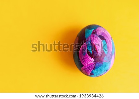Easter egg painted with acrylic on a yellow background. Happy Easter. Handmade author's painting of Easter eggs close-up view from above. Flat layout, bright colorful monochrome background. Copy space