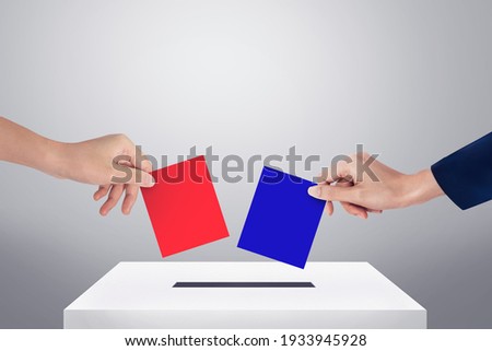 Hands holding red and blue ballot paper for election vote concept.
