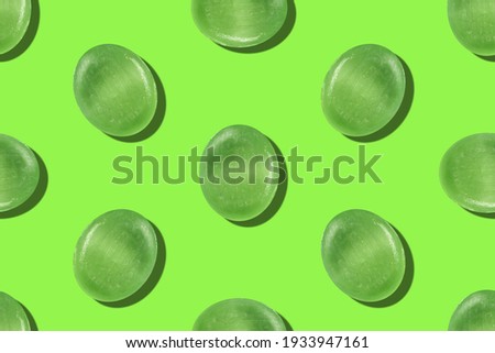 Seamless pattern of green mint ball lollipops above a green background. Festive background for holiday paper.