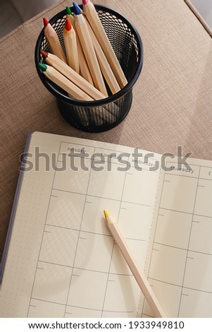 Empty and blank calendar and diary lying open viewed from above with a pencil next to it. Plan and to do list concept. Yellow and grey colors of the year.