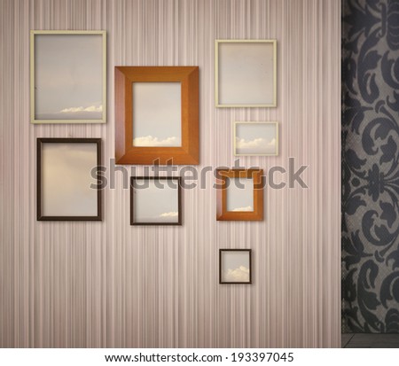Pink stripped wallpaper with hung a variety of picture frames with sky and clouds inside  