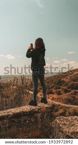 woman up on a wall taking photos with the mobile