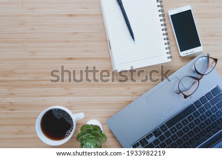 Work from home. desk office with laptop, blank notepad, coffee cup and pen on wood table. Flat lay top view copy spce.