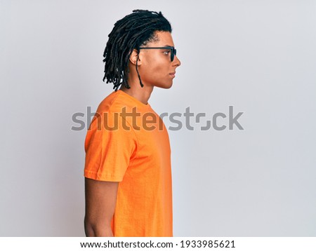 Young african american man wearing casual clothes and glasses looking to side, relax profile pose with natural face with confident smile.  Royalty-Free Stock Photo #1933985621
