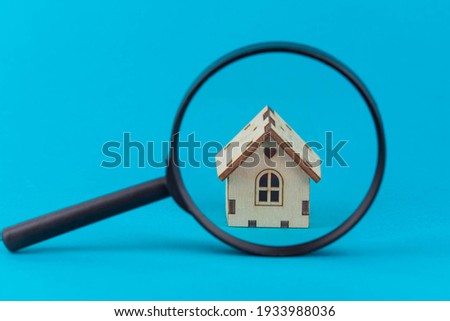 Find a home or a flat concept. Toy model house under magnifying glass. Rent apartments, Real Estate and buying a house idea. Blue background