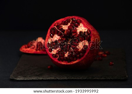Fresh tasty sweet peeled pomegranate with red seeds on dark black background, macro angle view. pomegranate seeds . High quality photo
