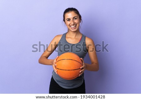 Young hispanic woman over isolated purple background playing basketball