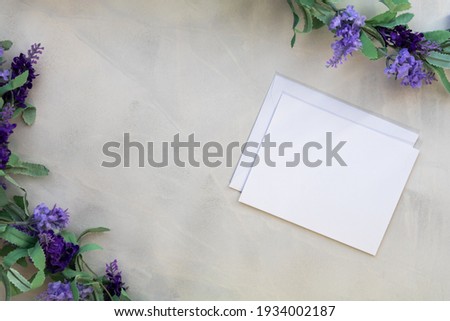 White notecard mockup and lilac on gray wash background flat lay copy space