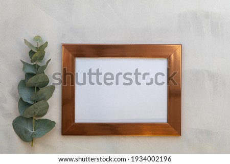 Rose gold frame mockup and eucalyptus on gray wash background flat lay copy space