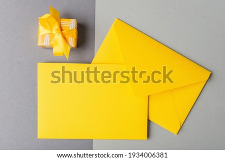 Yellow envelope with blank card and gift box on grey background