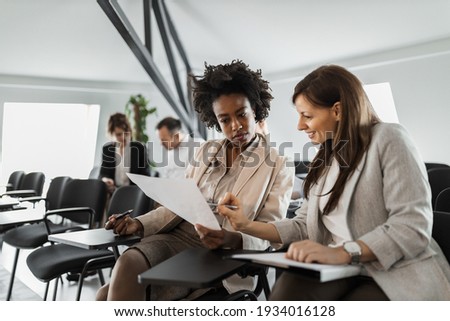 Group of people, making plans together, two females reading some documents. Royalty-Free Stock Photo #1934016128