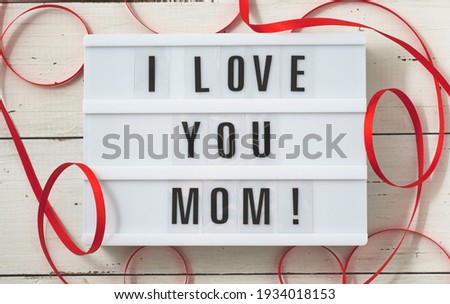 Happy Mother's Day Card. Love and happy mothers day card with red ribbon on white wooden rustic background.                              