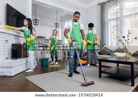 Team of diverse professional hardworking mixed race cleaners from cleaning service, working together in modern luxury house, using cleaning tools. Service industries concept. Royalty-Free Stock Photo #1934018414